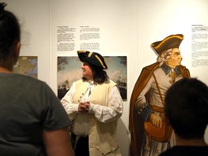 Une employée en costume d'époque fait faire une visite guidée du musée à un groupe de visiteurs. 