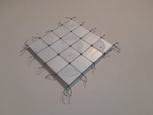 Dentelle de papier piquée et perlée sur contenant de poutine taillé et cousu dans un filet de pêche.